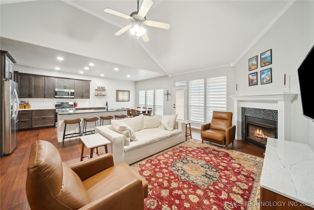 living room featuring ornamental molding, ceiling fan, dark wood-type flooring, a tile fireplace, and high vaulted ceiling