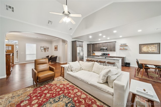 living room featuring ceiling fan, crown molding, dark wood-type flooring, and vaulted ceiling