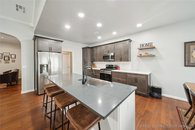 kitchen with a center island with sink, a kitchen breakfast bar, sink, dark hardwood / wood-style floors, and appliances with stainless steel finishes