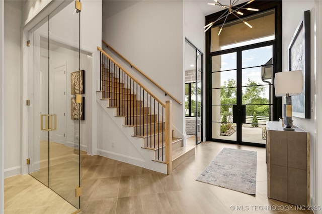 entryway with a chandelier, french doors, expansive windows, and a high ceiling