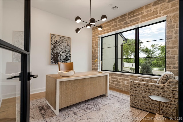 interior space featuring light hardwood / wood-style flooring, brick wall, and a notable chandelier