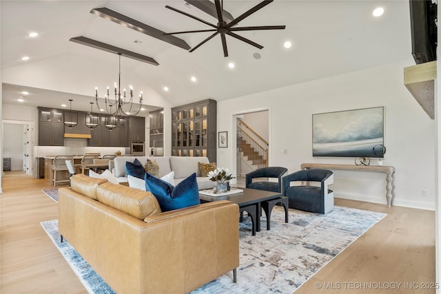 living room with ceiling fan with notable chandelier, lofted ceiling with beams, and light hardwood / wood-style flooring