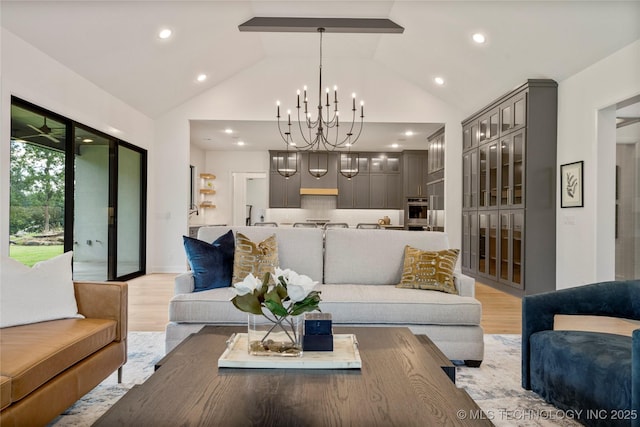 living room with light hardwood / wood-style flooring, lofted ceiling, and a notable chandelier