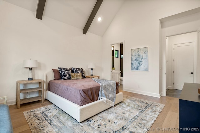 bedroom featuring beamed ceiling, light hardwood / wood-style flooring, high vaulted ceiling, and ensuite bath