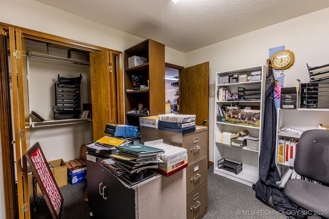 home office featuring dark carpet and a textured ceiling