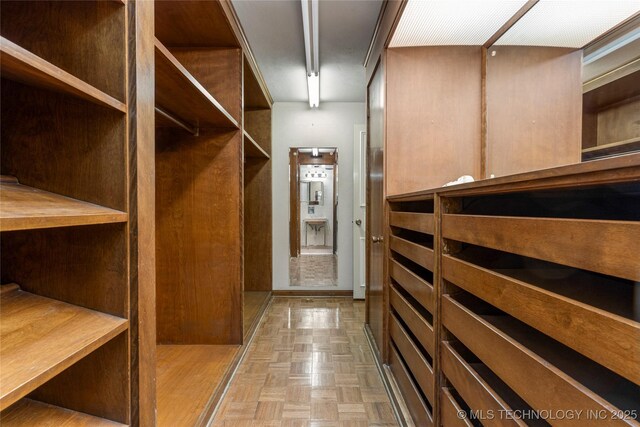 walk in closet with light parquet floors