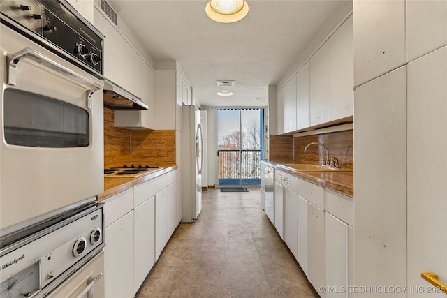 kitchen with white cabinets, white appliances, expansive windows, and sink