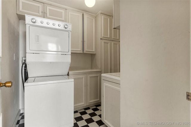 clothes washing area with cabinets and stacked washer and dryer