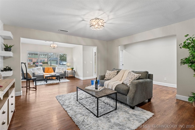 living room with dark hardwood / wood-style flooring, a chandelier, and a textured ceiling