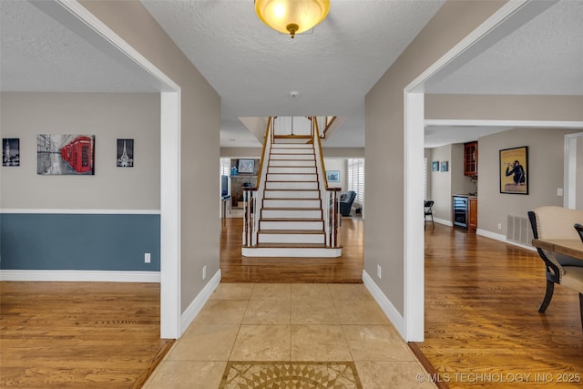 tiled foyer with beverage cooler and a textured ceiling