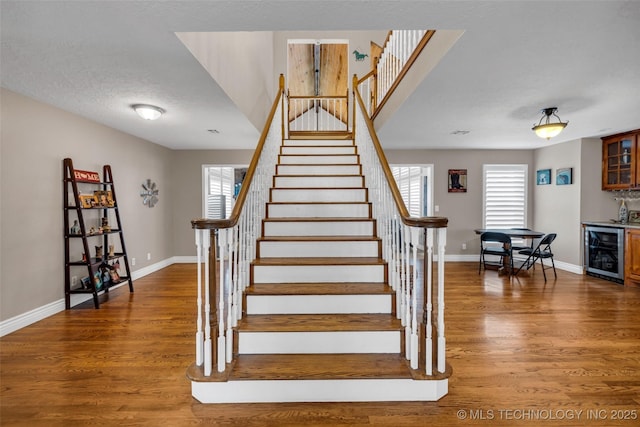 stairs featuring indoor bar, hardwood / wood-style flooring, wine cooler, and a wealth of natural light