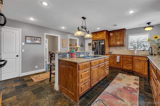 kitchen with a center island, backsplash, black appliances, sink, and hanging light fixtures