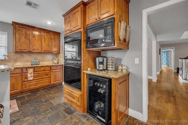 kitchen featuring light stone counters, wine cooler, and black appliances