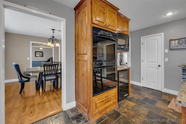 kitchen with beverage cooler, light stone counters, a notable chandelier, pendant lighting, and black appliances