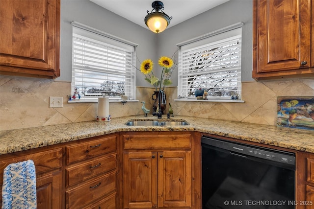 kitchen featuring dishwasher, backsplash, light stone counters, and sink