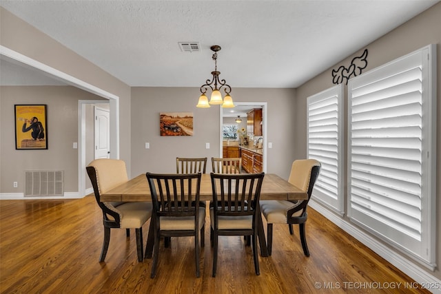 dining space featuring dark hardwood / wood-style flooring, a chandelier, and a textured ceiling