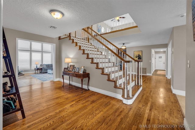 stairs featuring hardwood / wood-style floors and a textured ceiling