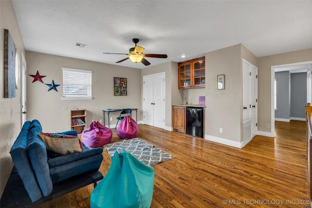 living room with wood-type flooring, sink, beverage cooler, and ceiling fan