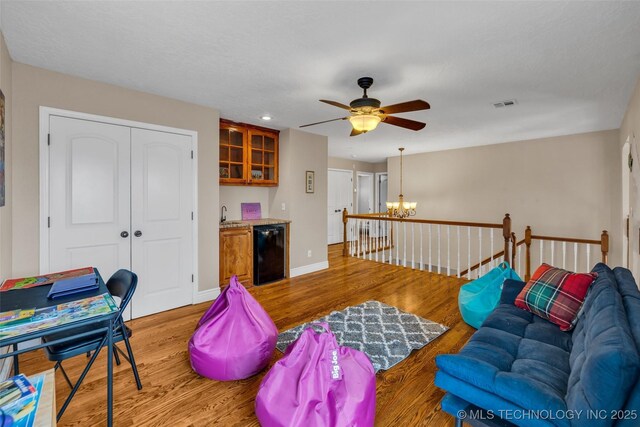 living room featuring sink, ceiling fan with notable chandelier, and light wood-type flooring