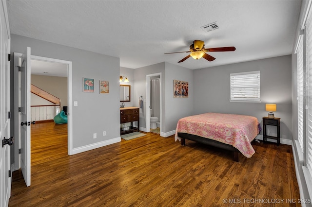 bedroom featuring a textured ceiling, dark hardwood / wood-style flooring, ensuite bathroom, and ceiling fan