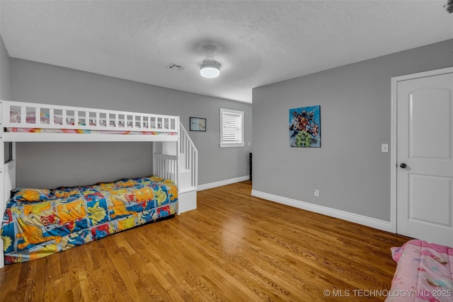 bedroom featuring hardwood / wood-style flooring, ceiling fan, and a textured ceiling