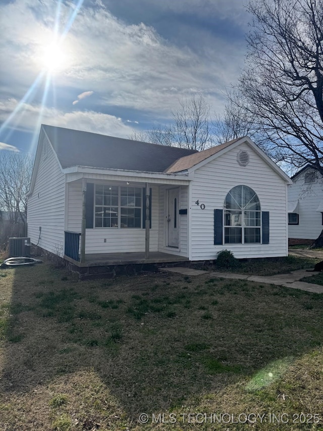 ranch-style home featuring a front yard, cooling unit, and covered porch