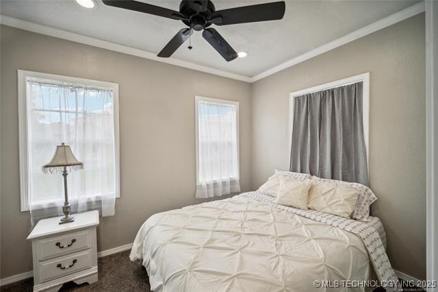 carpeted bedroom featuring multiple windows and ceiling fan