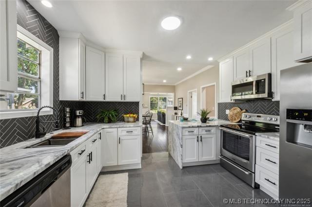 kitchen with white cabinets, appliances with stainless steel finishes, a healthy amount of sunlight, and sink