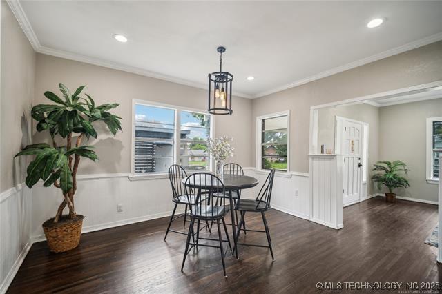 dining area with dark hardwood / wood-style flooring, an inviting chandelier, and ornamental molding