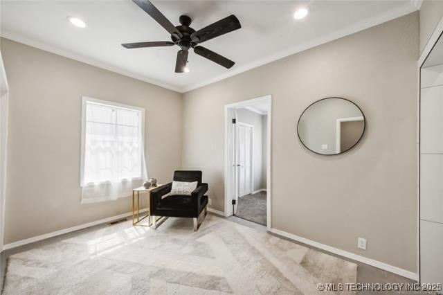 living area featuring crown molding, ceiling fan, and light colored carpet