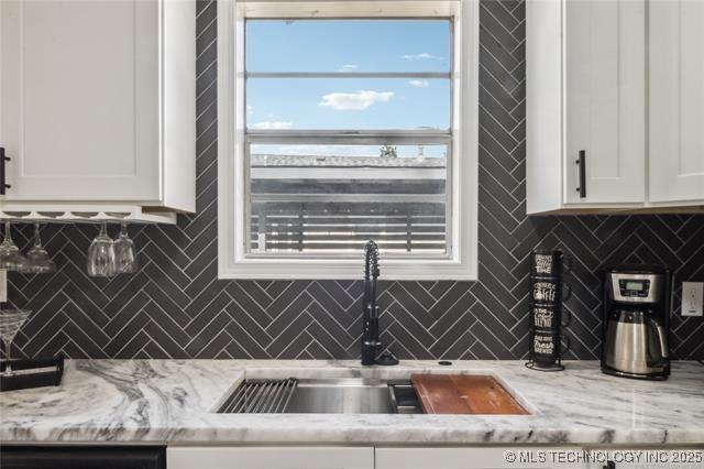 kitchen featuring white cabinets, light stone countertops, sink, and tasteful backsplash