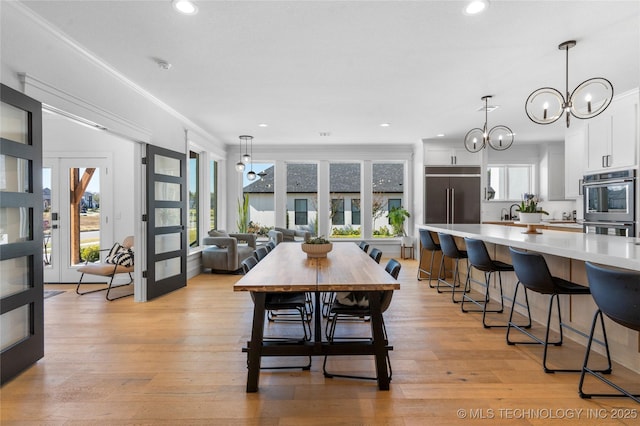 dining room with a chandelier, french doors, light hardwood / wood-style floors, and ornamental molding