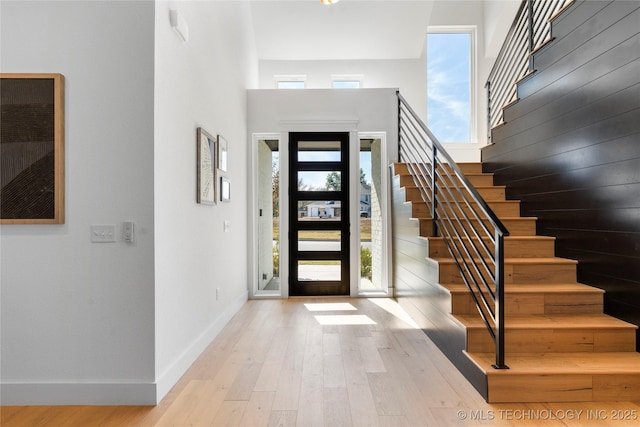 foyer entrance with a towering ceiling and light wood-type flooring