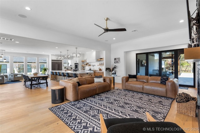 living room featuring ceiling fan with notable chandelier, light hardwood / wood-style floors, and ornamental molding