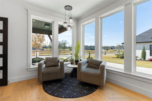 living area with wood-type flooring and ornamental molding