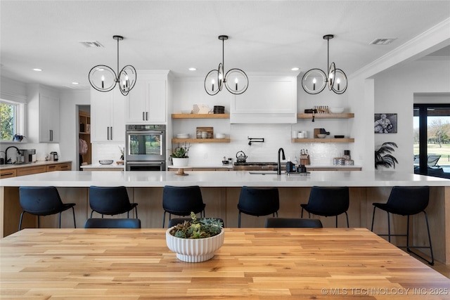 kitchen featuring a kitchen bar, sink, white cabinets, and double oven