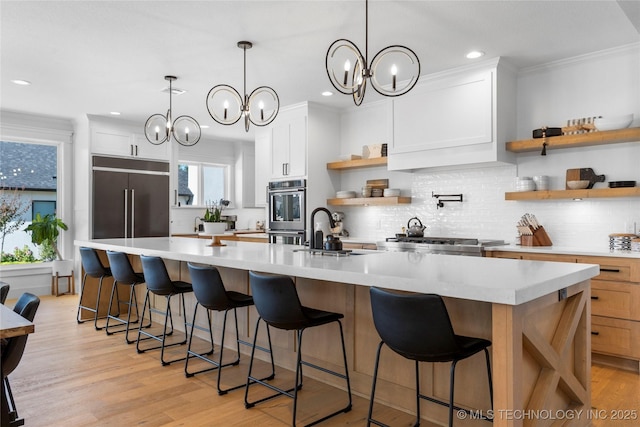 kitchen featuring stainless steel appliances, white cabinetry, a large island, and a notable chandelier