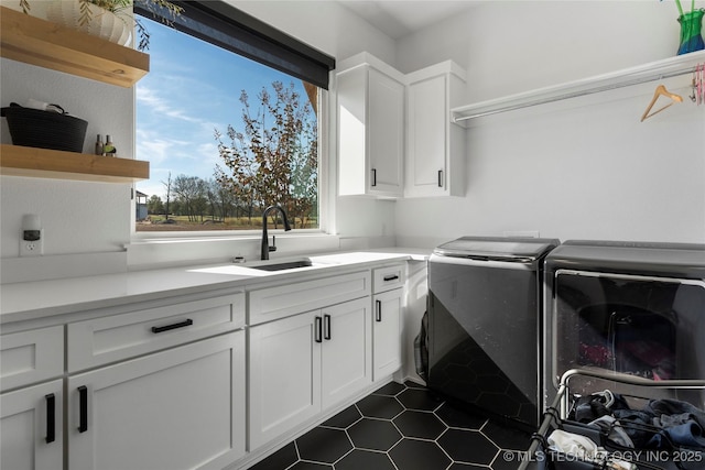 washroom featuring dark tile patterned flooring, cabinet space, a sink, and washer and clothes dryer