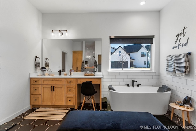 bathroom featuring tile patterned floors, vanity, a bath, and tile walls