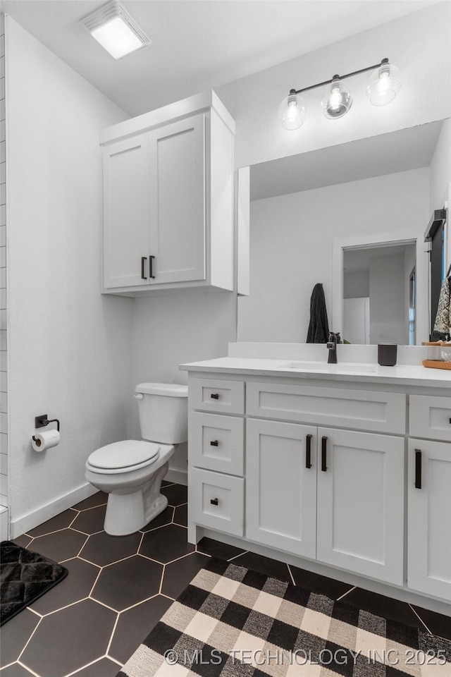 bathroom with baseboards, vanity, toilet, and tile patterned floors