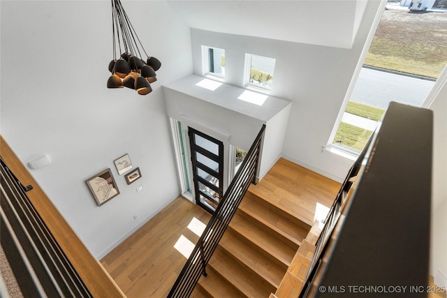 foyer entrance with stairway, an inviting chandelier, and wood finished floors