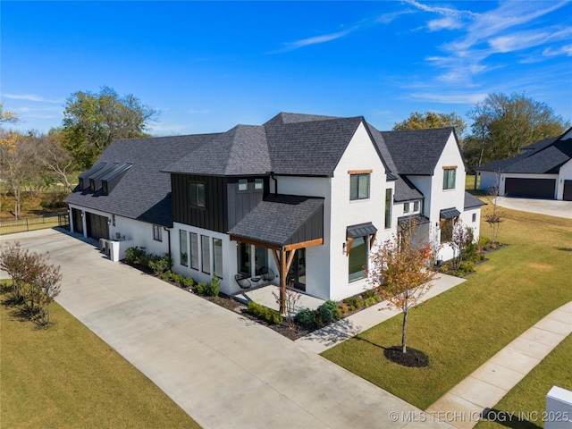 modern farmhouse with concrete driveway, a front yard, board and batten siding, and roof with shingles