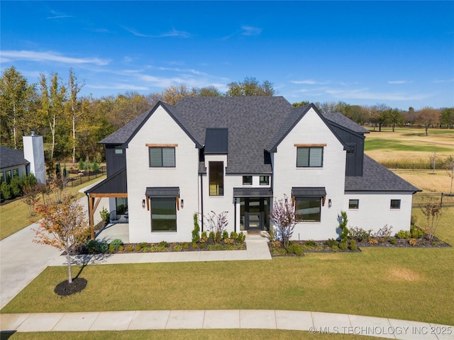 view of front of house featuring a shingled roof and a front yard