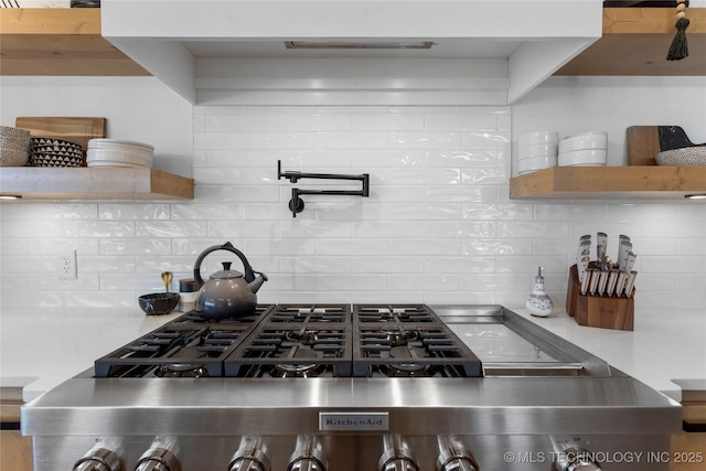 kitchen with range, open shelves, and backsplash