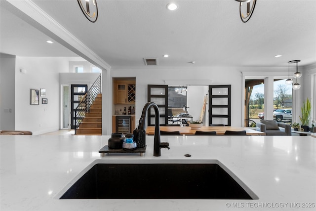 kitchen featuring wine cooler, crown molding, and sink