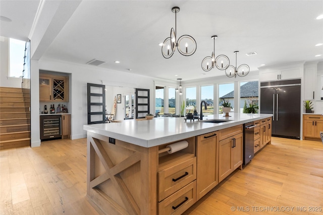 kitchen with a spacious island, sink, wine cooler, built in refrigerator, and a notable chandelier