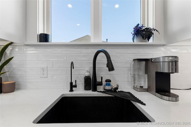 interior details featuring white cabinets, tasteful backsplash, light countertops, and a sink