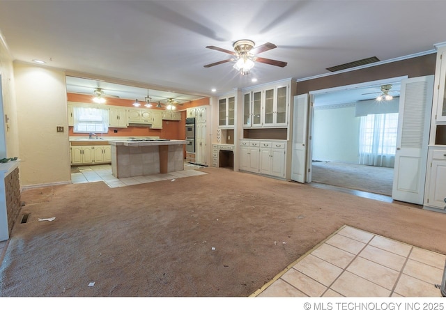 kitchen with sink, double oven, light colored carpet, a breakfast bar, and a kitchen island