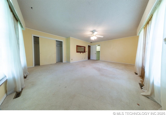 unfurnished bedroom with a textured ceiling, a closet, ceiling fan, and light colored carpet