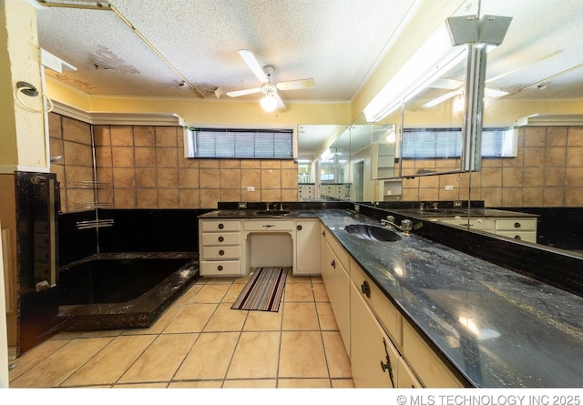 kitchen featuring white cabinetry, sink, tasteful backsplash, a textured ceiling, and light tile patterned floors